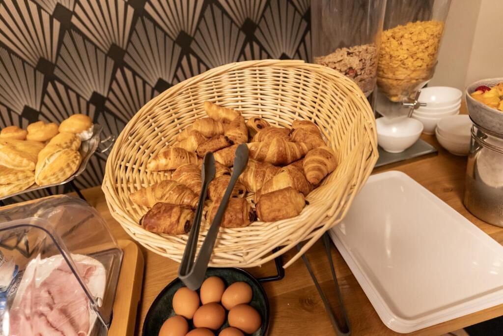Un bufé de desayuno con croissants, huevos y una cesta de mimbre.
