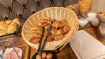 Un bufé de desayuno con croissants, huevos y una cesta de mimbre.
