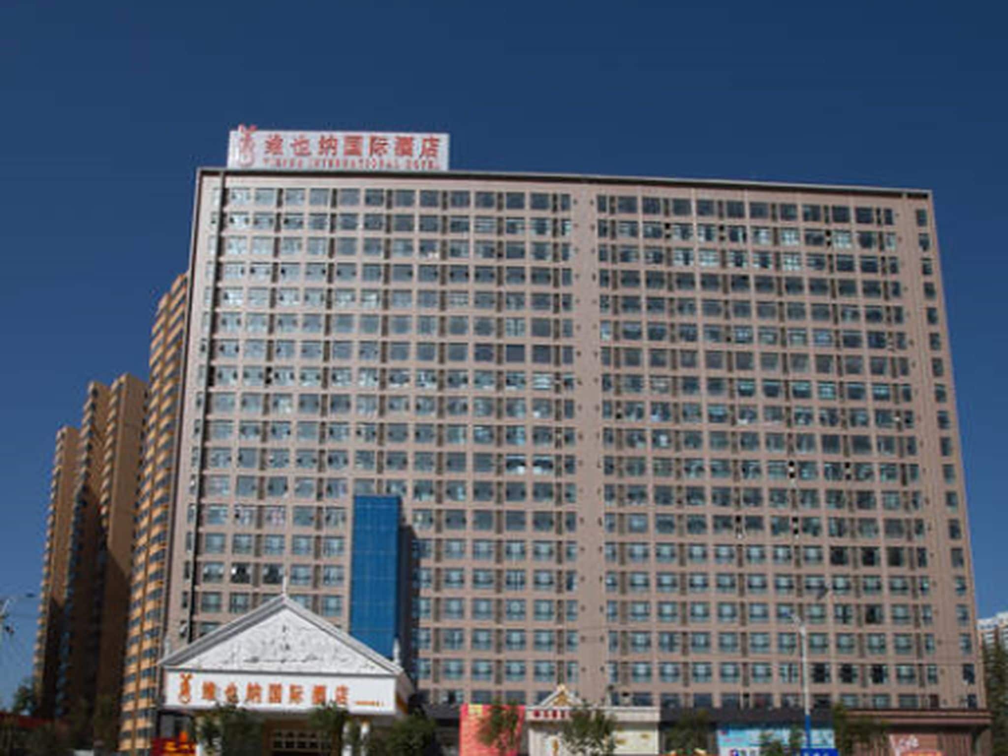 A high-rise building with a large number of windows and a sign at the top.