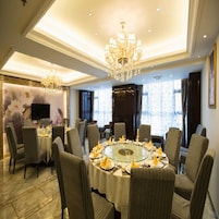 Comedor formal con una mesa redonda, sillas, candelabros y un amplio ventanal con cortinas.