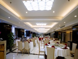 Un restaurante espacioso con varias mesas y sillas, un techo alto con iluminación empotrada y vista al salón comedor.