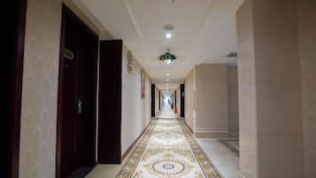 A hotel corridor with a patterned floor, doors on both sides, and a ceiling light fixture.
