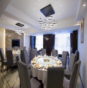 A conference room with a round table, chairs, and modern lighting fixtures. - Vienna International Hotel (Zhumadian)