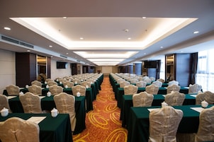 A conference room with rows of tables and chairs, equipped with projectors and a large screen.