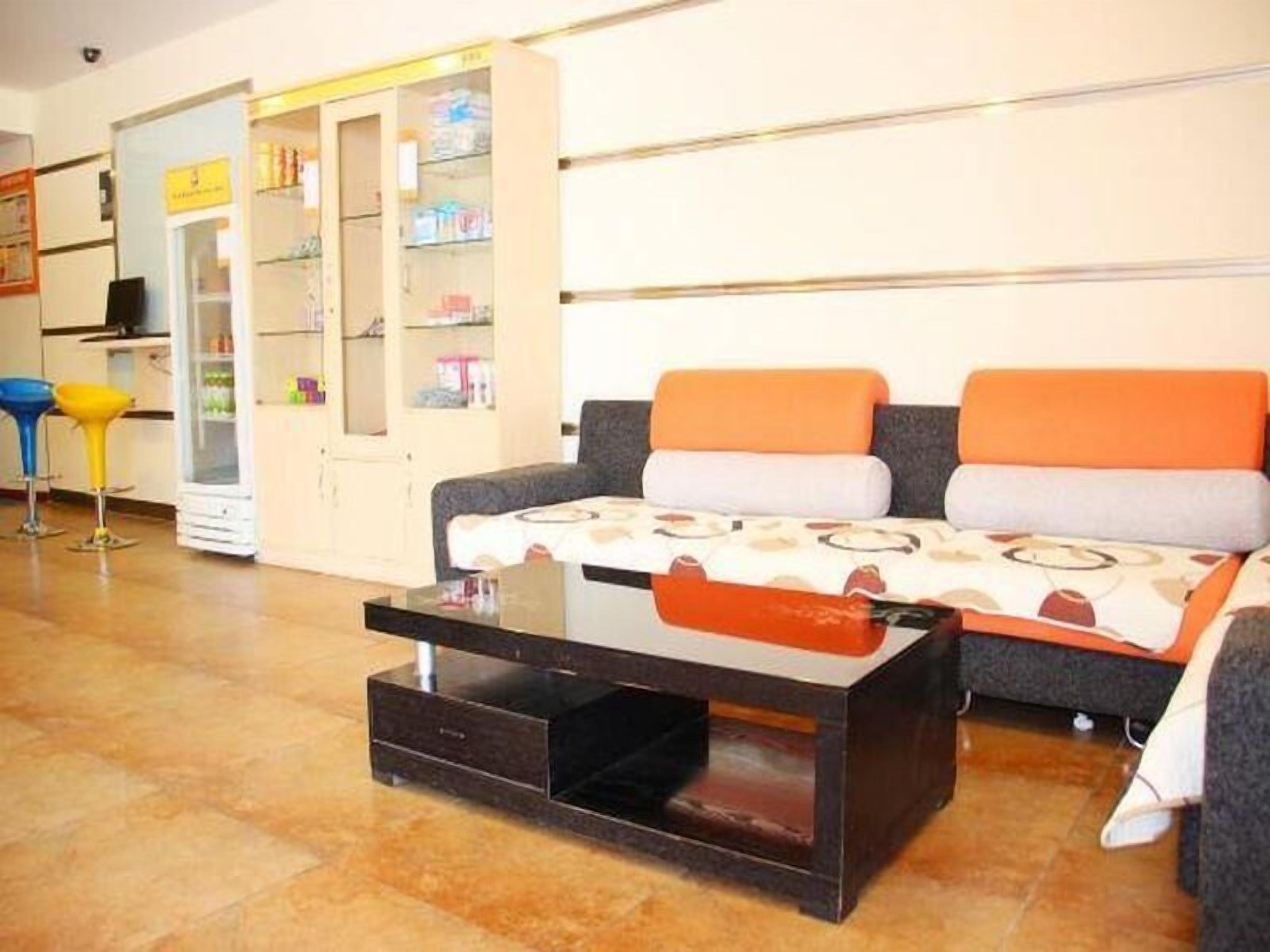 Una sala de estar con un sofá, una mesa de centro, un aparador con estantes y una silla.
