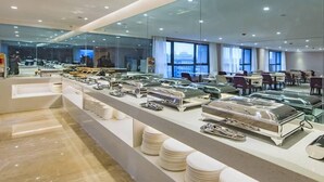 Ein moderner Essbereich mit Glastrennwänden, Buffetbedienung und Blick auf die Stadt durch große Fenster.