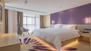 Ein modernes Hotelzimmer mit einem großen Bett, einem Schreibtisch, einem Stuhl und Blick ins Freie.