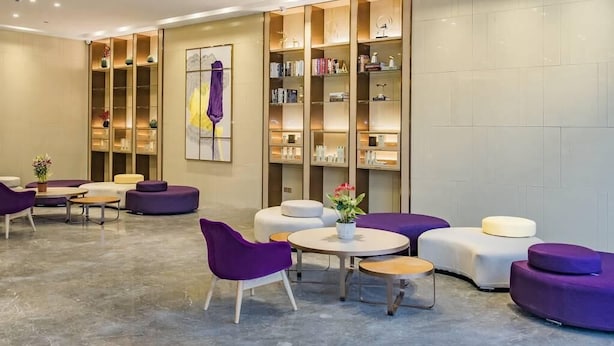 Eine moderne Lobby mit Sitzbereichen, einem Empfangstresen und einem großen Bücherregal.