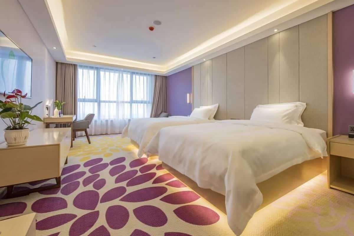 A hotel room with a bed, a desk, a chair, and a large window.