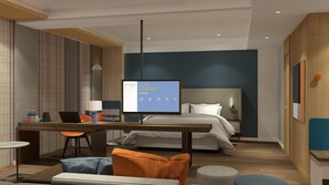 A modern hotel room with a bed, desk, chair, lamp, and a digital screen displaying a message. - Holiday Inn Express Qiliping by IHG (Leshan)