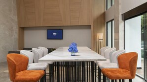 A modern conference room with a marble table, white and orange chairs, and a blue flower centerpiece. - Holiday Inn Express Qiliping by IHG (Leshan)