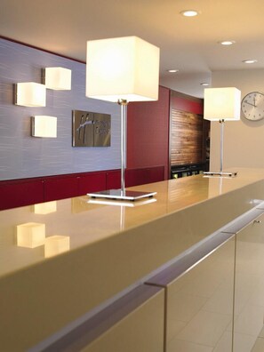 A modern reception desk with a clock, wall-mounted lamps, and a plaque. - Holiday Inn Express Qiliping by IHG (Leshan)