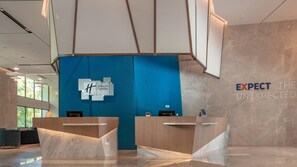 A Holiday Inn Express reception desk with a blue accent wall and a large 'H' logo. - Holiday Inn Express Qiliping by IHG (Leshan)