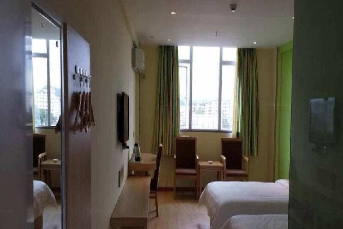 A hotel room with two beds, a desk, a chair, a TV, and a window with curtains.