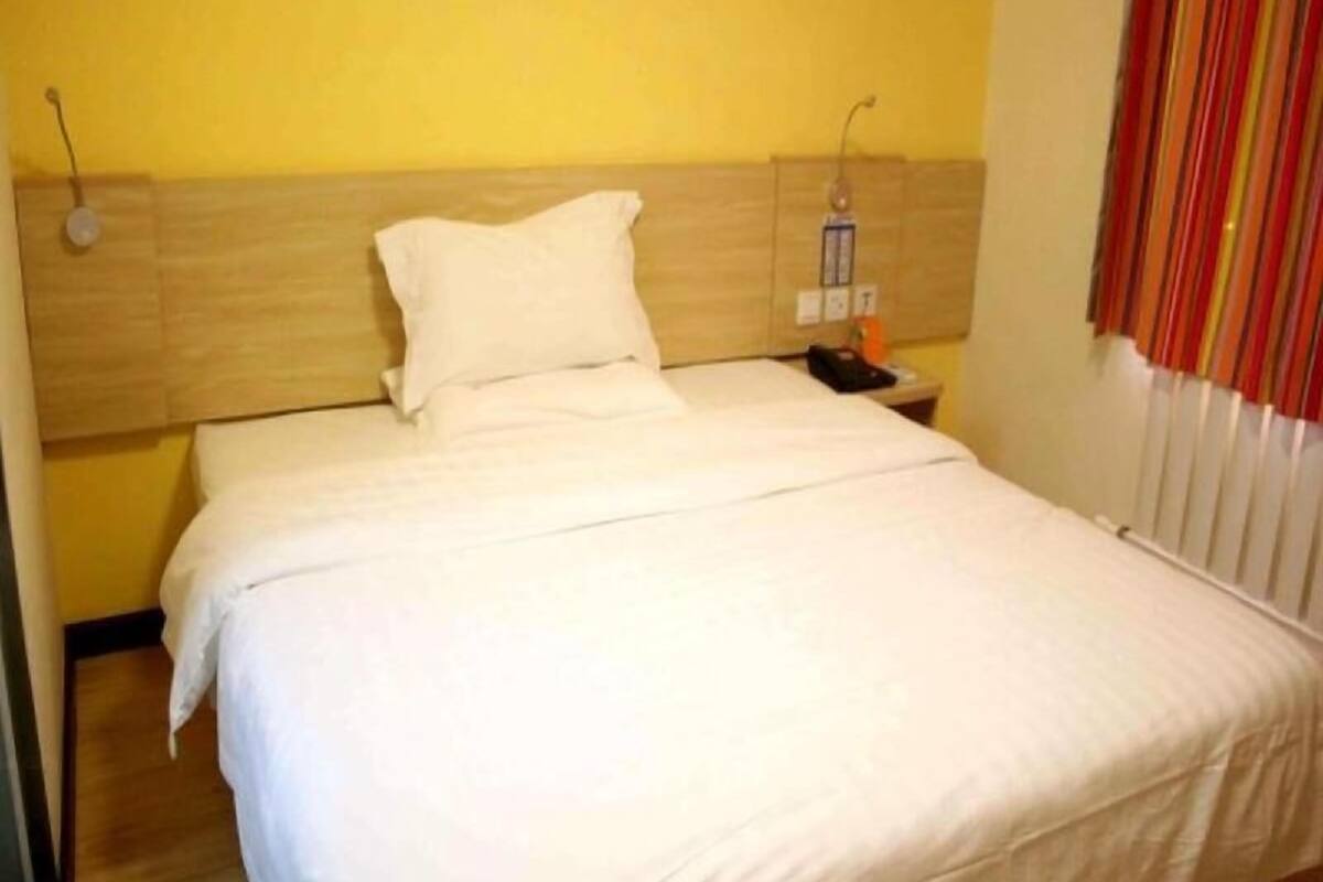 A hotel room with a bed, a nightstand, and a telephone.