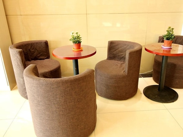 Un espace détente avec des tables rondes et des chaises rembourrées, chacune agrémentée d’une petite plante.