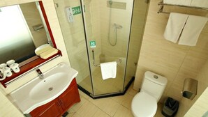 A bathroom with a glass-enclosed shower, a sink with a mirror, a toilet, and a towel rack.