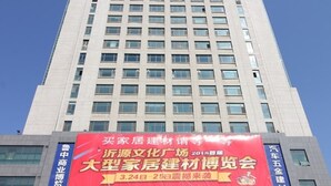A multi-story building with a large banner advertising a home construction material exhibition.