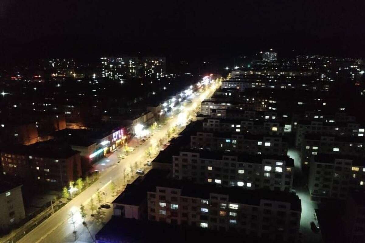 A nighttime cityscape with illuminated buildings and a busy street.
