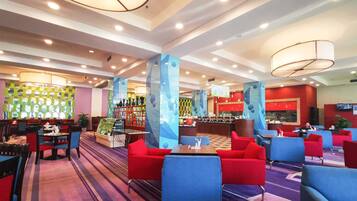 A hotel lobby with multiple seating areas, a reception desk, and a bar.