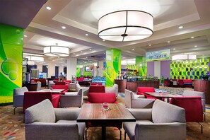 Een hotel lobby met verschillende zithoeken, een bar en een kinderspeelruimte.