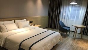 A hotel room with a large bed, a chair, a small table, and a nightstand. - City Comfort Inn Hotel (Wuhan)