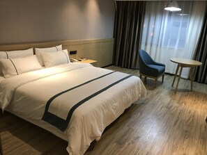 Una habitación de hotel con una cama grande, una silla, una mesita y una mesita de noche.