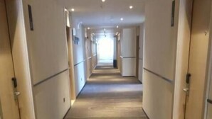 A hotel corridor with carpeted floors, doors on both sides, and a light source at the end. - City Comfort Inn Hotel (Wuhan)