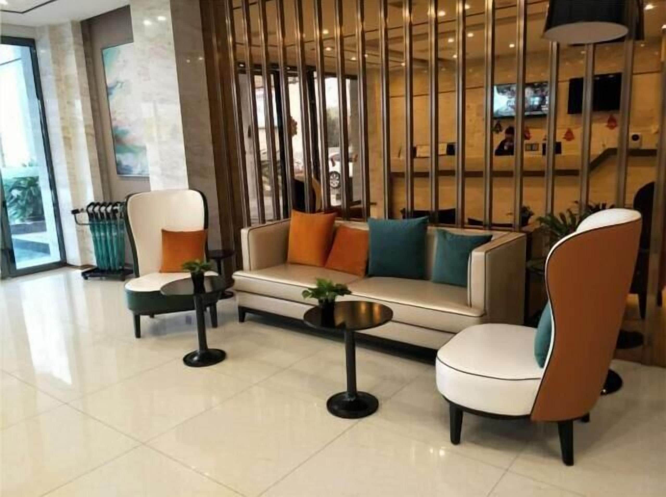 Eine moderne Lobby mit einer Couch, Sesseln, einem Couchtisch und einem dekorativen Raumteiler.