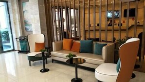 A modern lobby with a sofa, chairs, a coffee table, and a decorative partition. - City Comfort Inn Hotel (Wuhan)