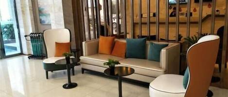 A modern lobby with a sofa, chairs, a coffee table, and a decorative partition.