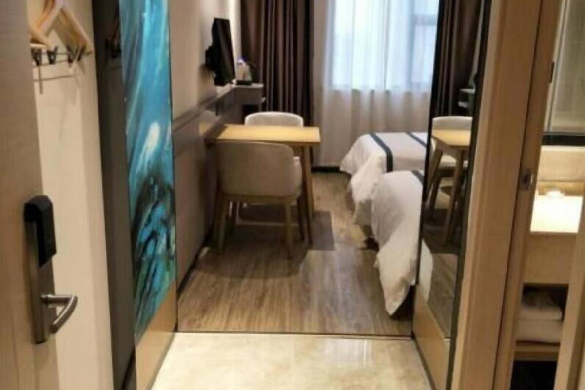 Une chambre d’hôtel équipée d’un bureau, d’une chaise, d’un lit et d’un grand miroir.