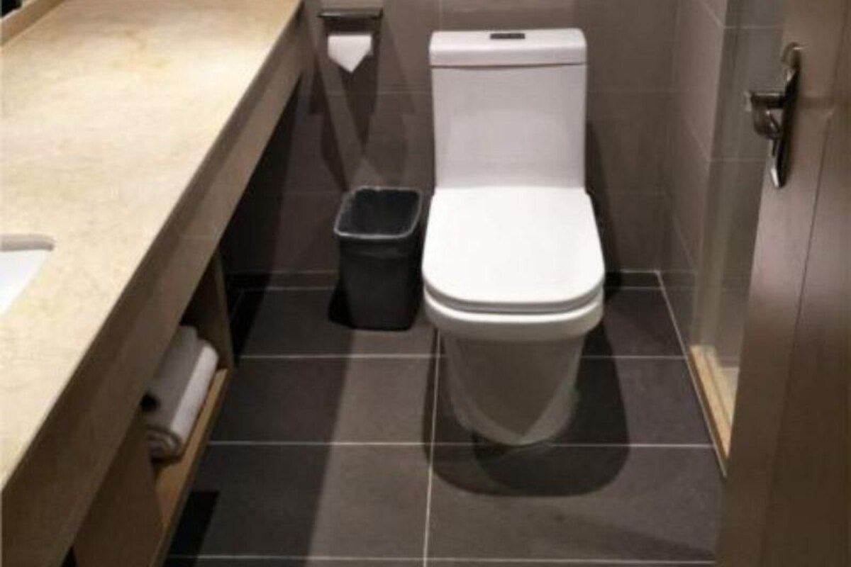 A small, modern bathroom with a toilet, a trash bin, and a countertop.