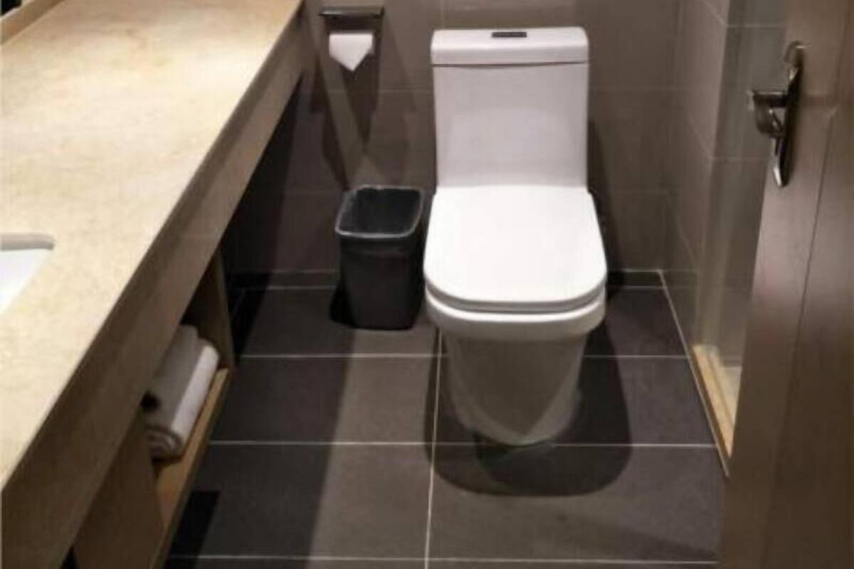 Une petite salle de bain moderne, équipée de toilettes, d’une poubelle et d’un plan de travail.