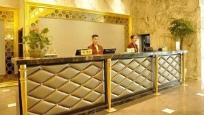 A reception desk with a marble wall backdrop, a potted plant, and a nameplate. - Crowne Plaza Zhengzhou by IHG (Zhengzhou)