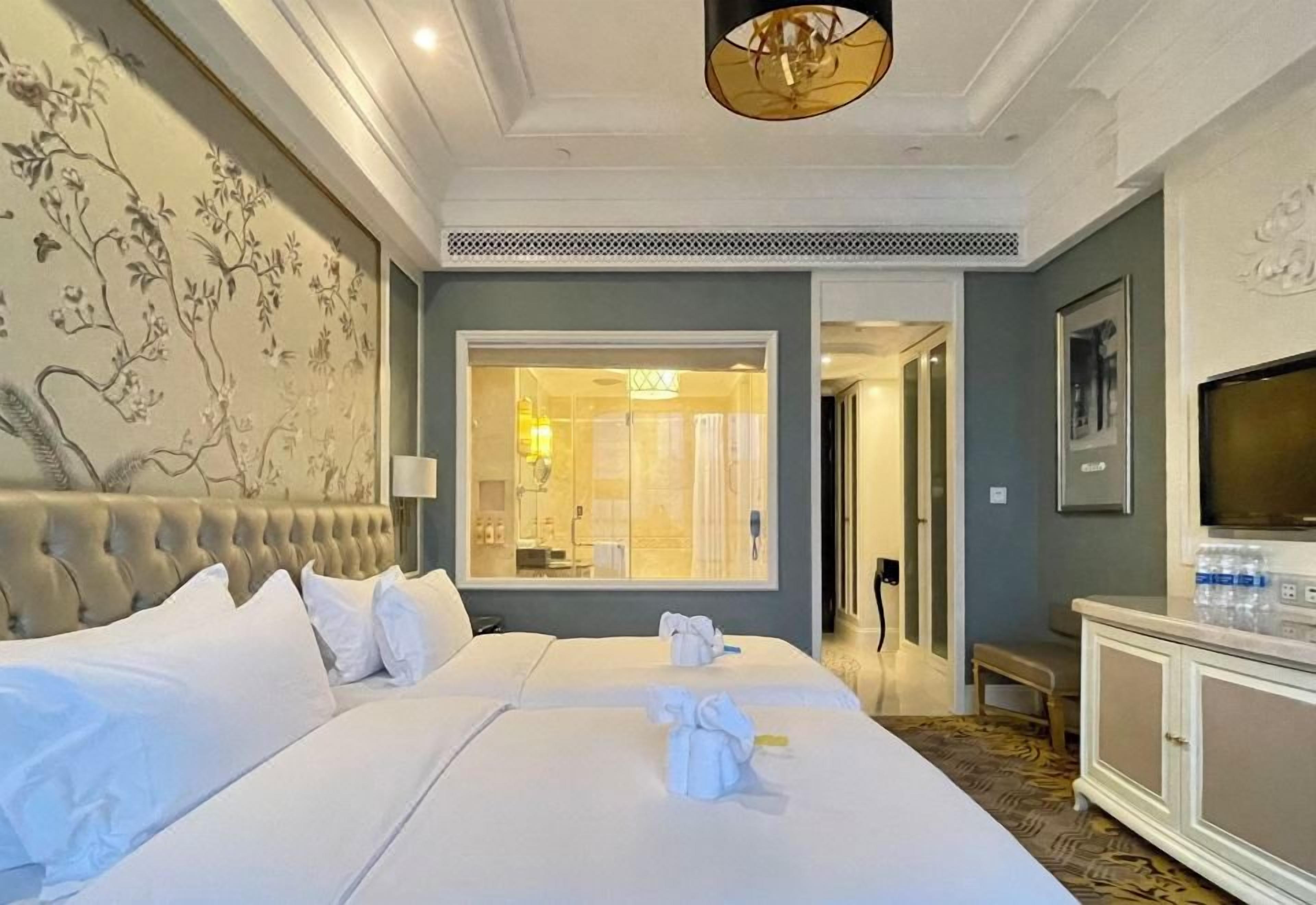Een hotelkamer met een groot bed, een televisie, een kledingkast en een badkamer zichtbaar door een geopende deur.