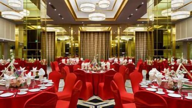 A banquet hall with round tables, red chairs, and a central aisle. - Crowne Plaza Zhengzhou by IHG (Zhengzhou)