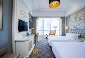 A hotel room with a large bed, a desk with a flat-screen TV, a chair, and a window with a view. - Crowne Plaza Zhengzhou by IHG (Zhengzhou)
