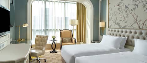 A hotel room with a bed, a desk, a chair, a TV, and a window with curtains.