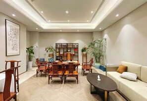 A modern living room with a dining area, featuring wooden furniture, a sofa, and a coffee table. - Crowne Plaza Zhengzhou by IHG (Zhengzhou)