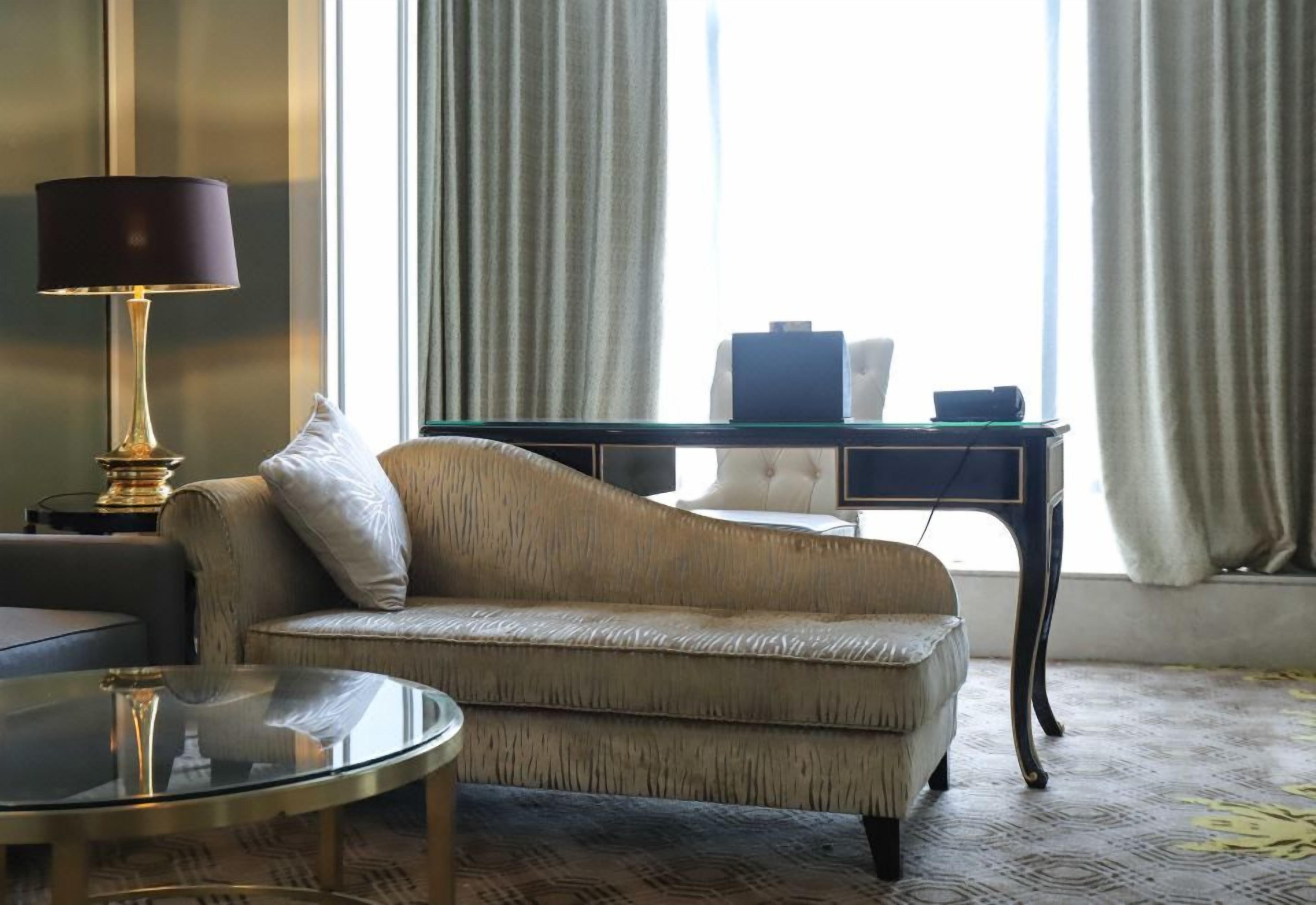 Un salon avec un canapé, une table basse en verre, une lampe, un bureau et une chaise.