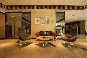 Un hall con dos sillones modernos, una mesita y una pared con cuadros enmarcados.