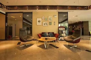 Un hall con dos sillones modernos, una mesita y una pared con cuadros enmarcados.
