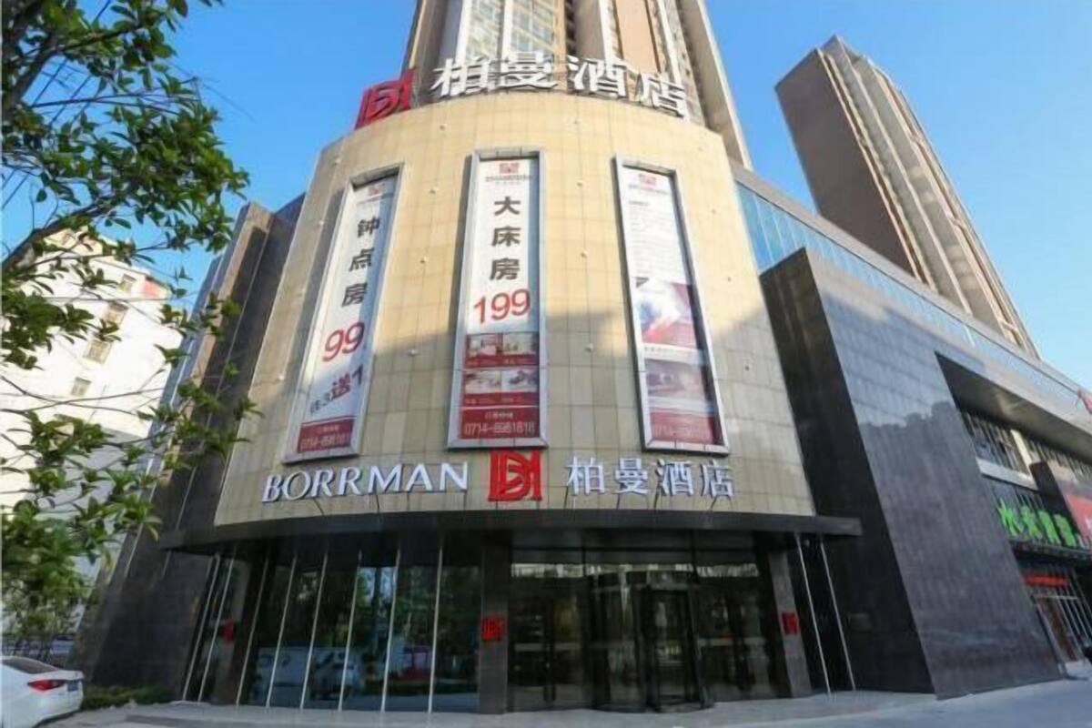 A hotel with a modern facade, large signage, and multiple advertisements.
