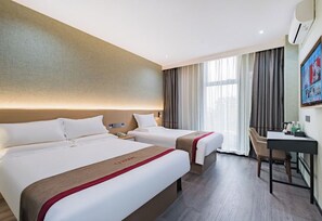 Ein Hotelzimmer mit zwei Betten, einem Schreibtisch und einem großen Fenster mit Vorhängen.