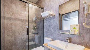 A modern bathroom with a glass shower enclosure, a white toilet, a sink with a marble countertop, and a towel rack. - Shankee Hotel (Shunyi)