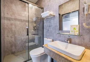 Ein modernes Badezimmer mit Duschkabine aus Glas, einer weißen Toilette, einem Waschbecken mit Marmorplatte und einem Handtuchhalter.