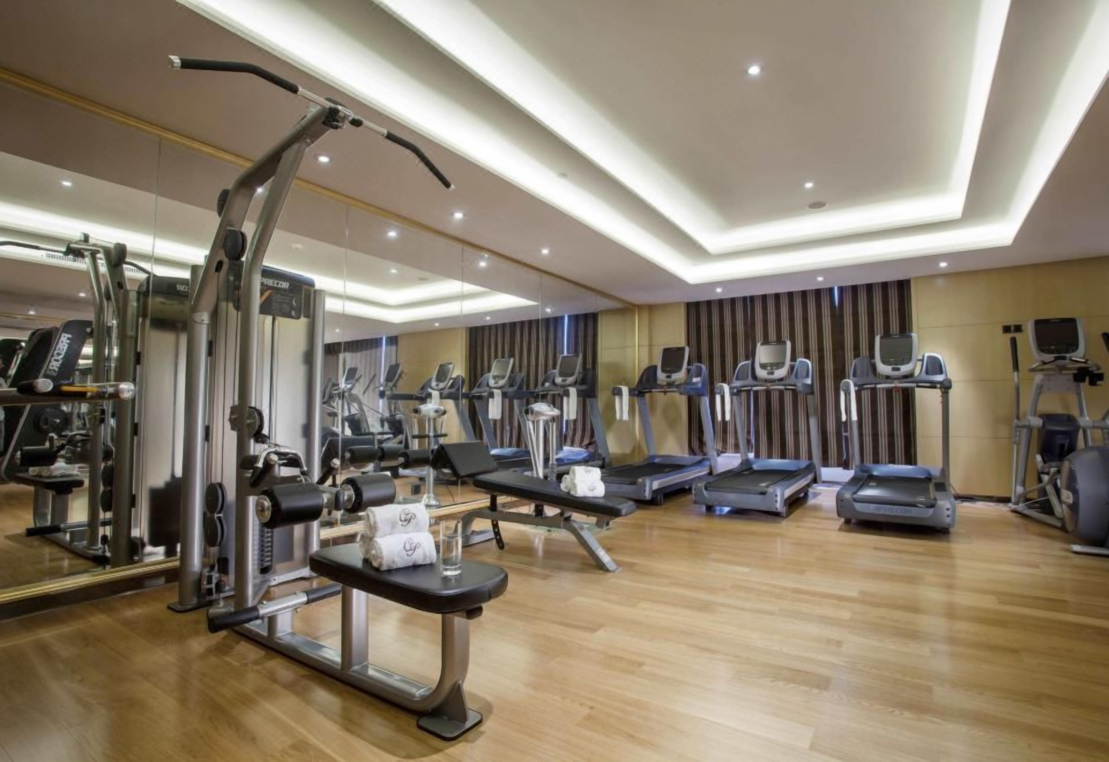 A gym with various exercise equipment, including treadmills, elliptical machines, and weight machines.