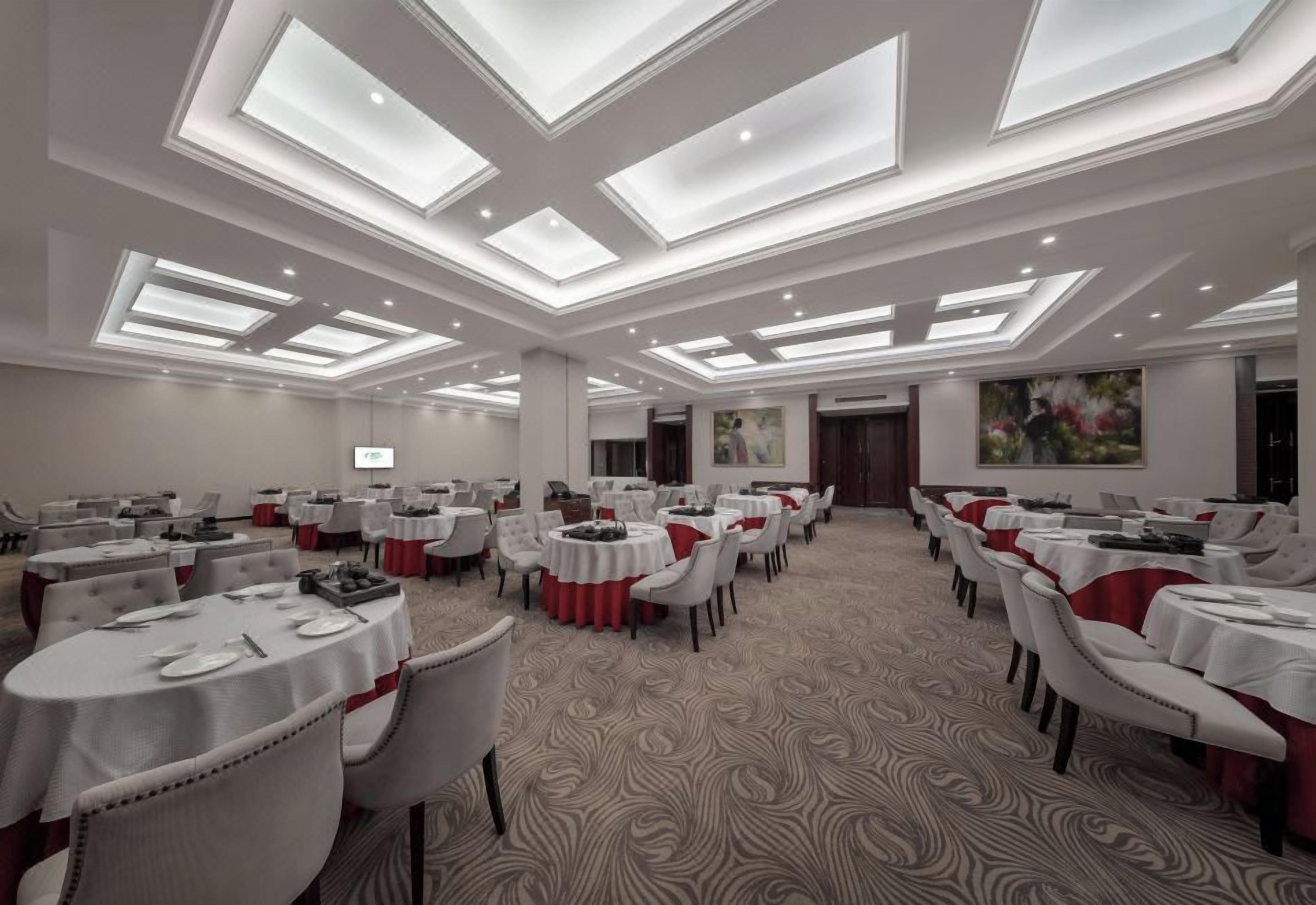 A conference room with multiple round tables, white tablecloths, and red accents.