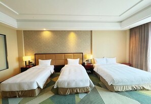 A hotel room with three single beds, a large headboard, and a patterned carpet. - Holiday Inn Foshan Nanhai Central by IHG (Foshan)
